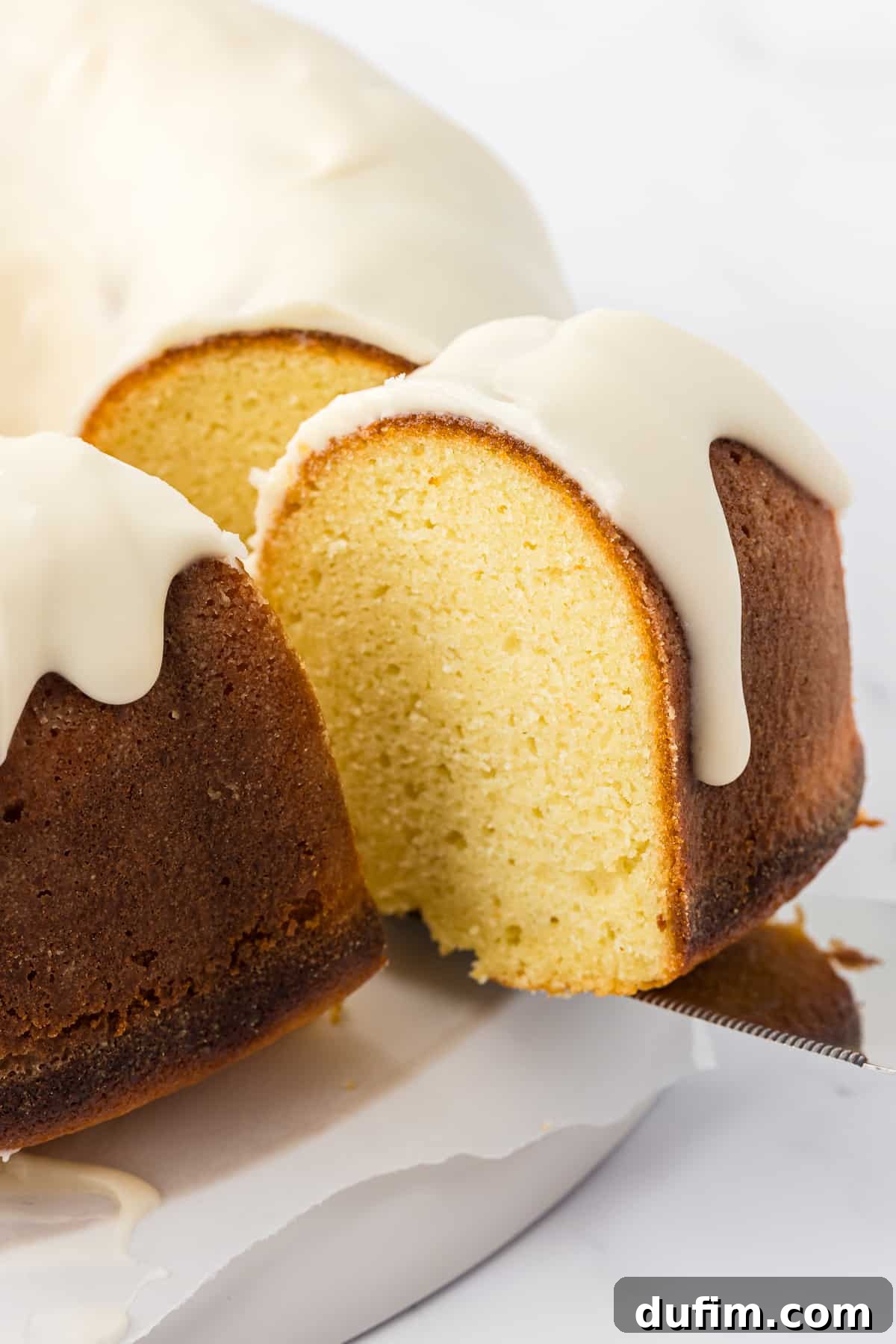 a slice of vanilla bundt cake being lifted away from the rest of the cake with a spatula