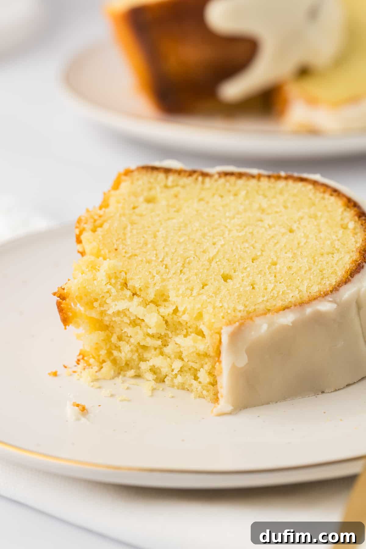 a slice of vanilla bundt cake on a small white plate with a bite missing out of it