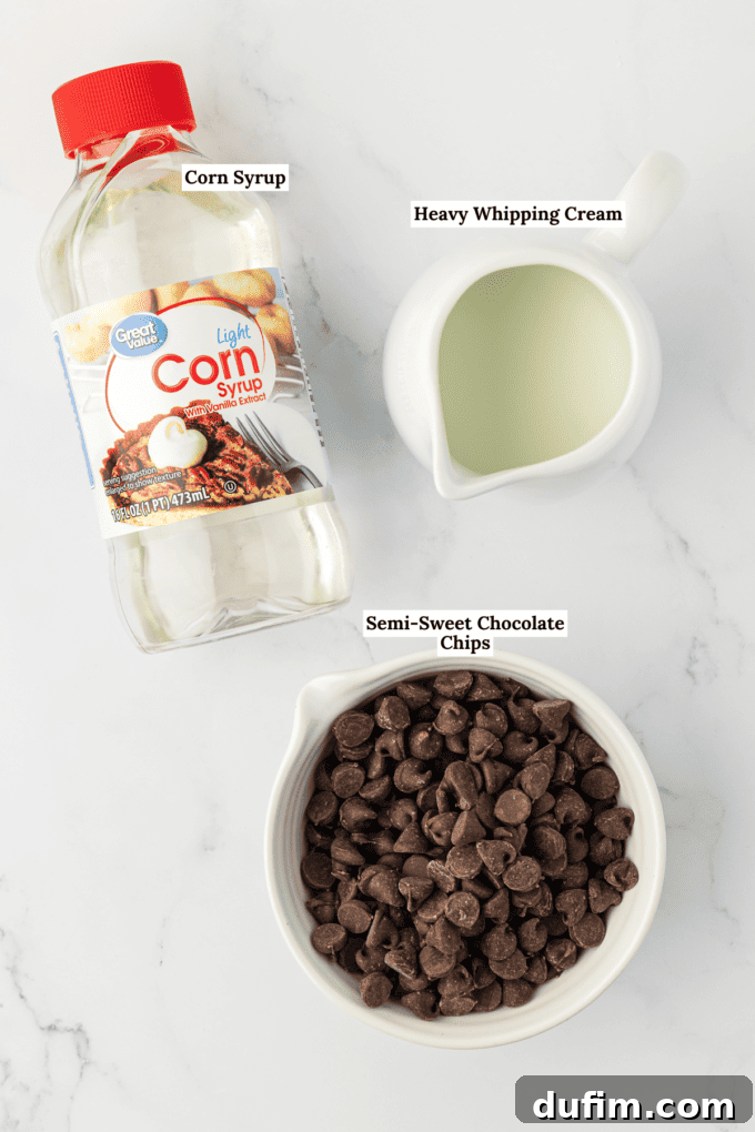 Overhead view of the ingredients for chocolate glaze including a bottle of corn syrup, a white dish full of heavy whipping cream, and a white bowl of semi-sweet chocolate chips