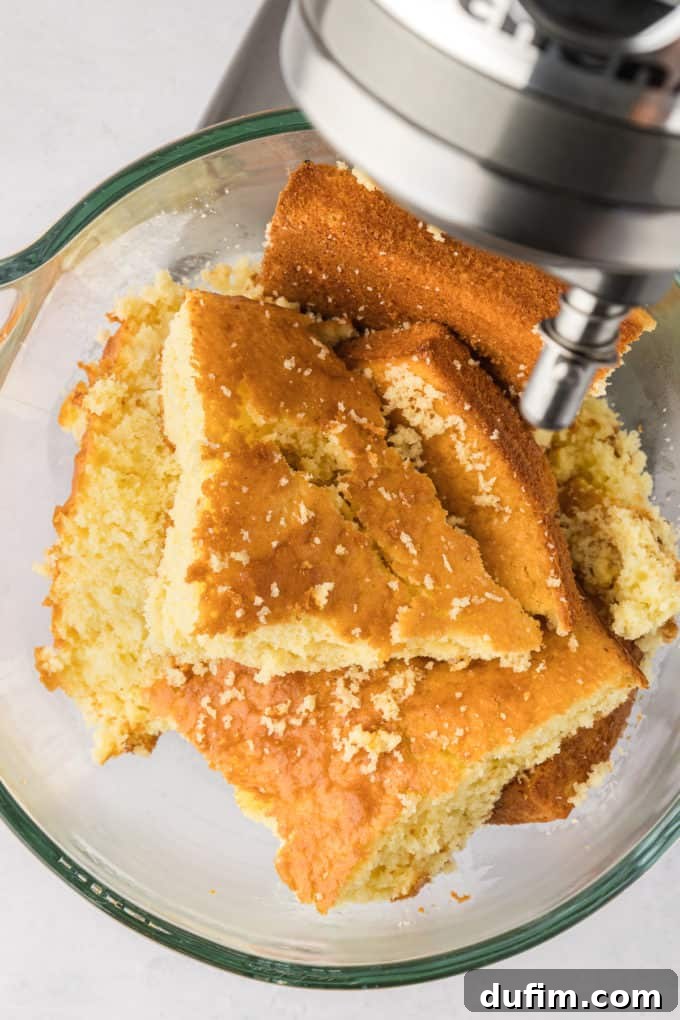 Crumbled pieces of freshly baked cake inside an electric mixing bowl, presenting a textured base ready to be combined with frosting for the next stage of cake pop creation.