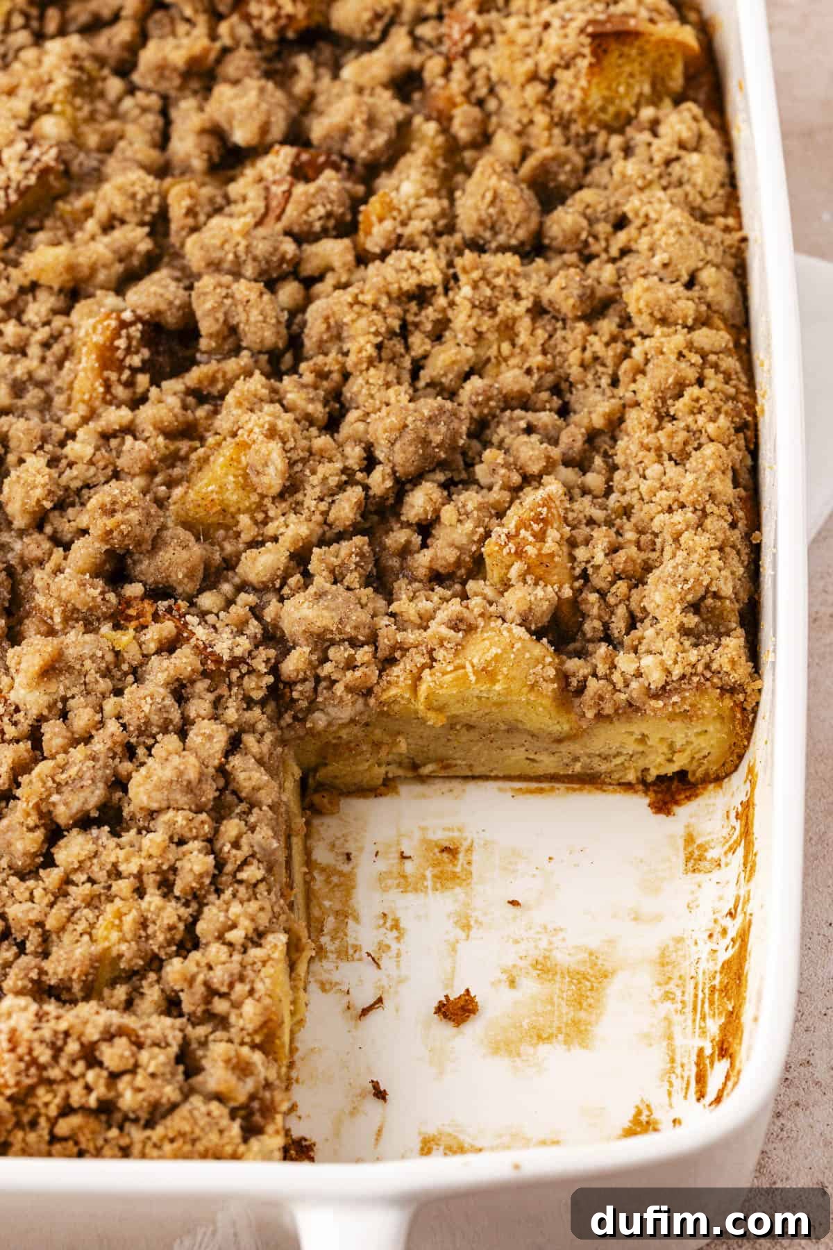 close up of a white baking dish full of french toast casserole missing one slice