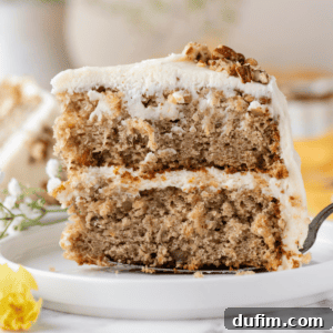 A piece of two-layer hummingbird cake being placed on a white plate with a spatula, showing the rich frosting and moist layers.