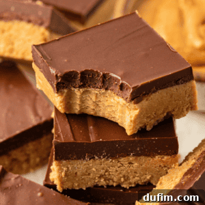 A stack of peanut butter bars with a bite out of the top bar and more bars scattered all around, enticing with their delicious layers.