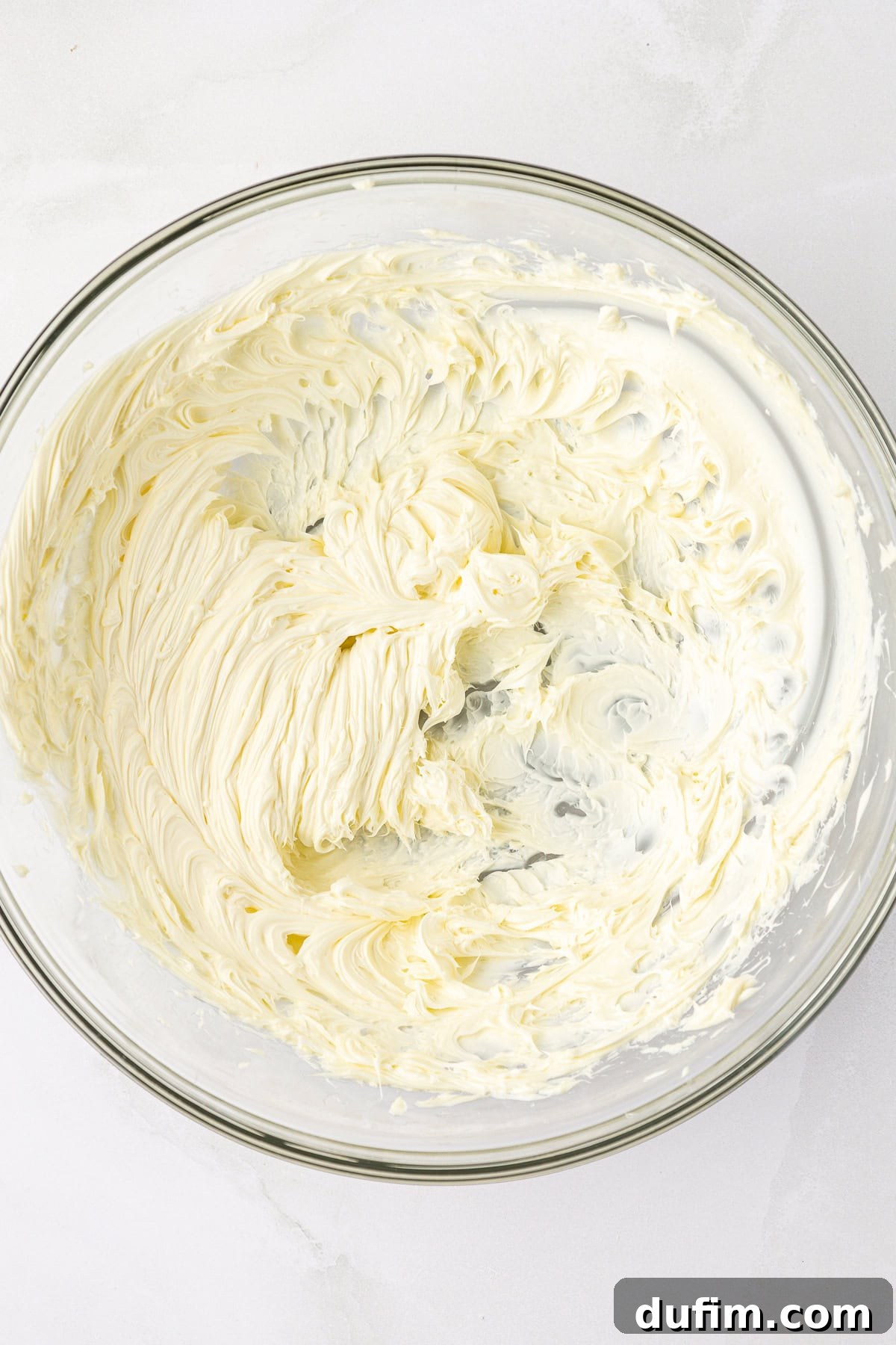 Creamed unsalted butter in a clear glass bowl, soft and fluffy, ready for the next step in making a homemade pound cake.