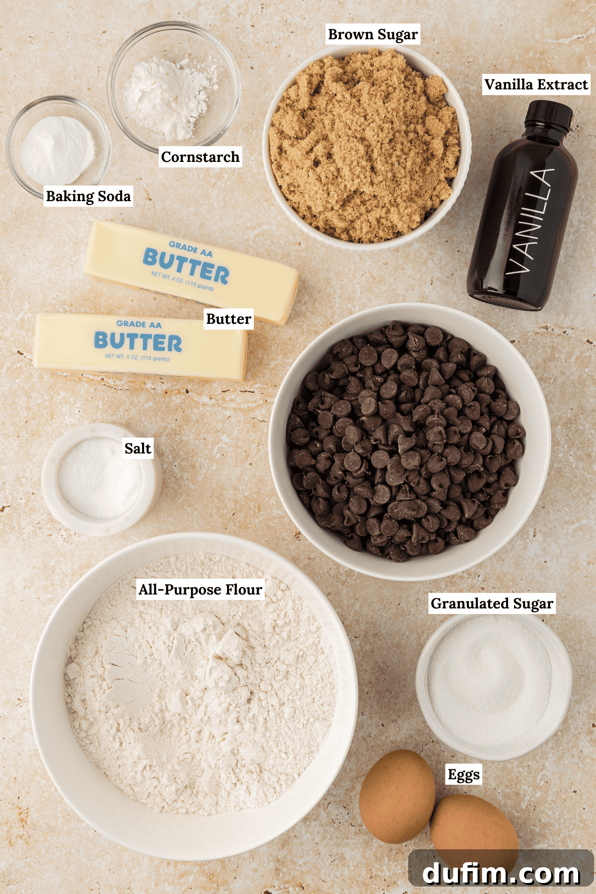 An artfully arranged overhead view of all the essential ingredients for a perfect pizookie: baking soda, cornstarch, rich brown sugar, pure vanilla extract, golden butter, luscious chocolate chips, a pinch of salt, all-purpose flour, granulated sugar, and fresh eggs.