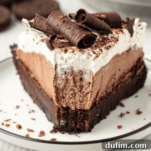 a slice of mud pie on a small white plate with a bite missing out of the tip of the pie