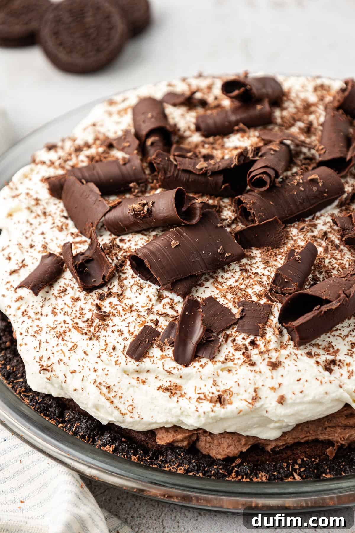 mud pie in a glass pie dish topped with chocolate shavings with whole oreos in the background