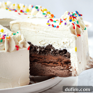 A slice of ice cream cake being lifted away from the rest of the cake with a spatula, displaying the perfect layers.