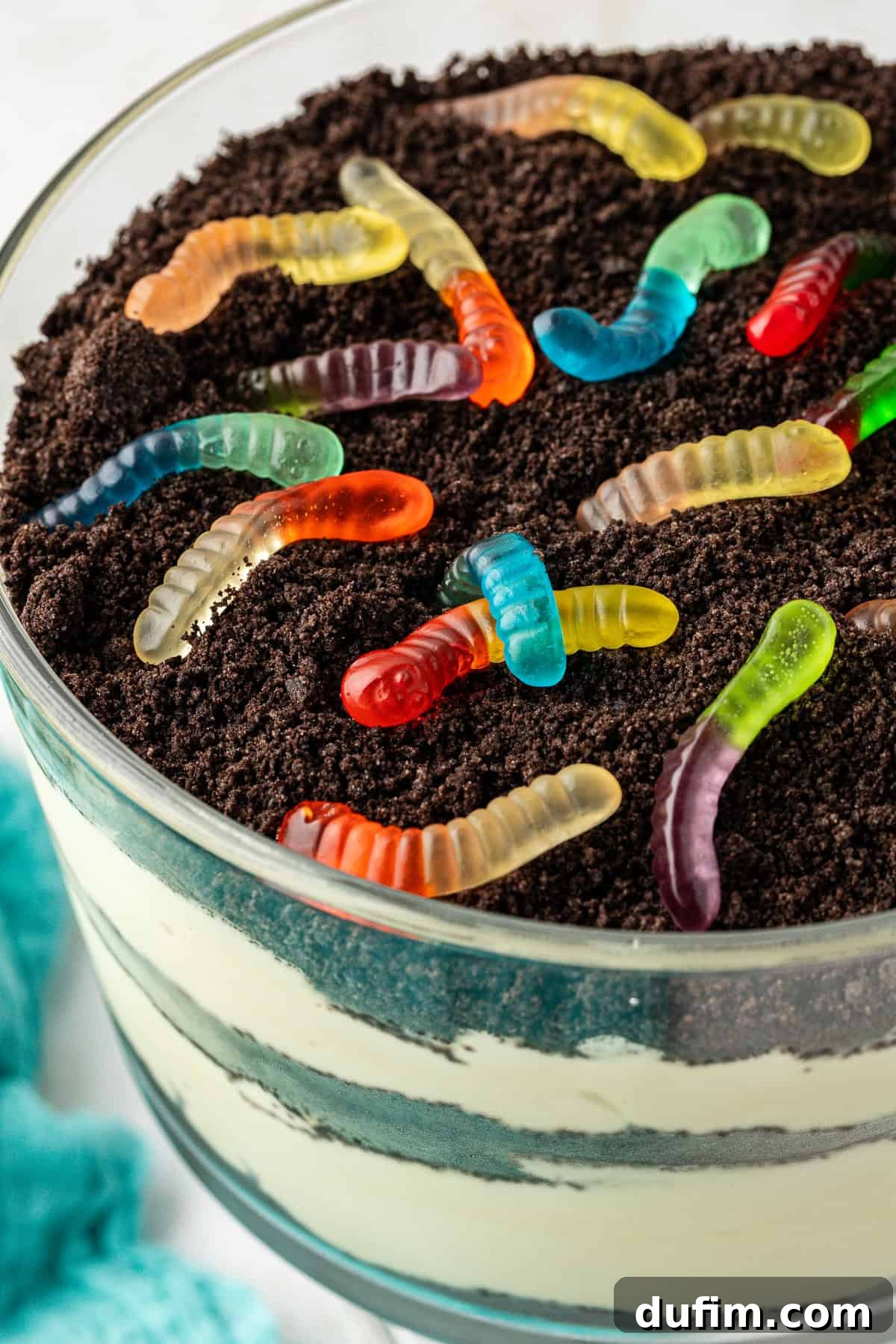 Mastering Delicious Dirt Cake 2 Close up of a large trifle bowl of rich, creamy dirt cake, generously topped with crushed Oreo cookies and playful gummy worms, showcasing its irresistible texture and fun presentation.
