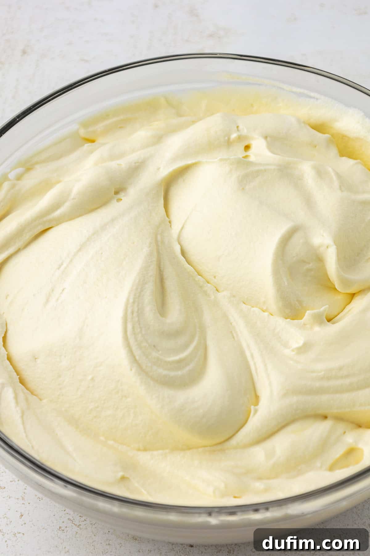 Mastering Delicious Dirt Cake 12 A large clear glass bowl showcasing the perfectly mixed milk and vanilla instant pudding, a creamy and smooth foundation for the dirt cake.