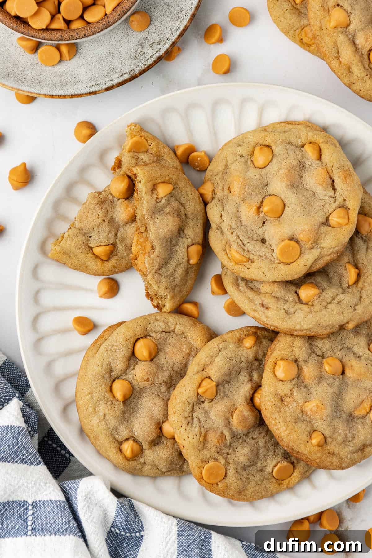Sweet Butterscotch Chip Delights 15 Overhead view of a delightful plate piled high with butterscotch cookies, most whole but one broken in half to reveal its tender interior. More cookies, a bowl of butterscotch chips, and scattered chips complete the appetizing scene.