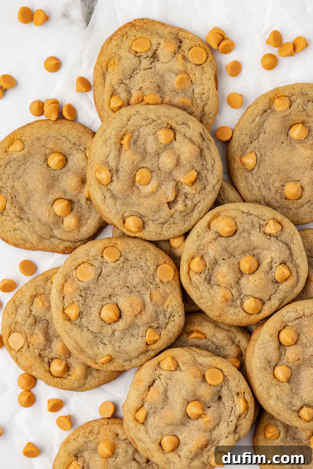 Sweet Butterscotch Chip Delights 16 Overhead view of a delectable pile of butterscotch cookies, glistening with melted chips and surrounded by loose butterscotch chips for a tempting visual.