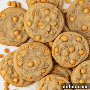 A delectable pile of golden butterscotch cookies, with loose butterscotch chips scattered around for a tempting visual.