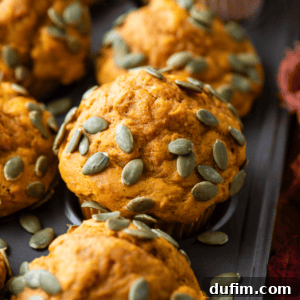close up of pumpkin muffins topped with pumpkin seeds in a muffin pan
