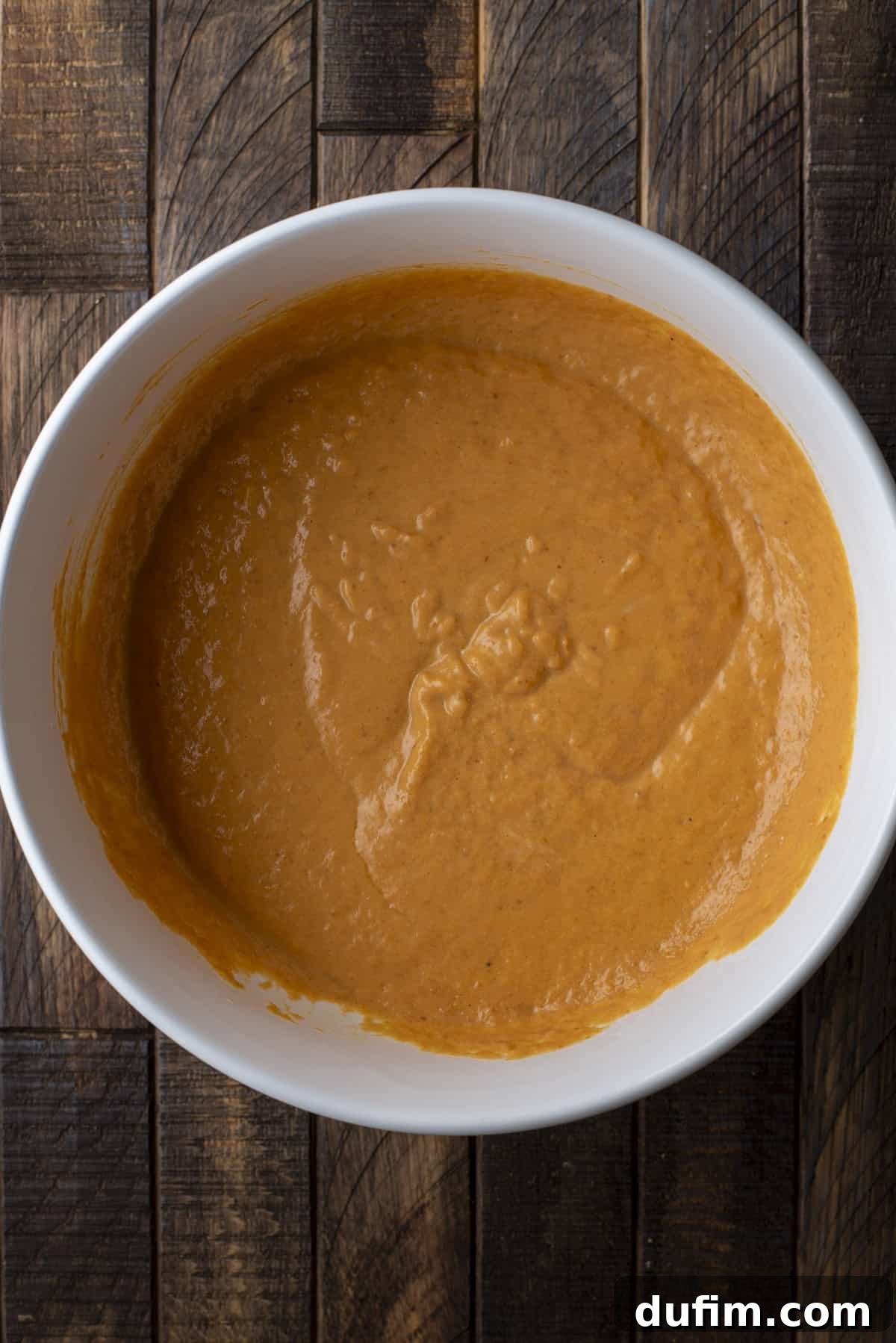 overhead view of wet ingredients for pumpkin muffins mixed in a large white bowl