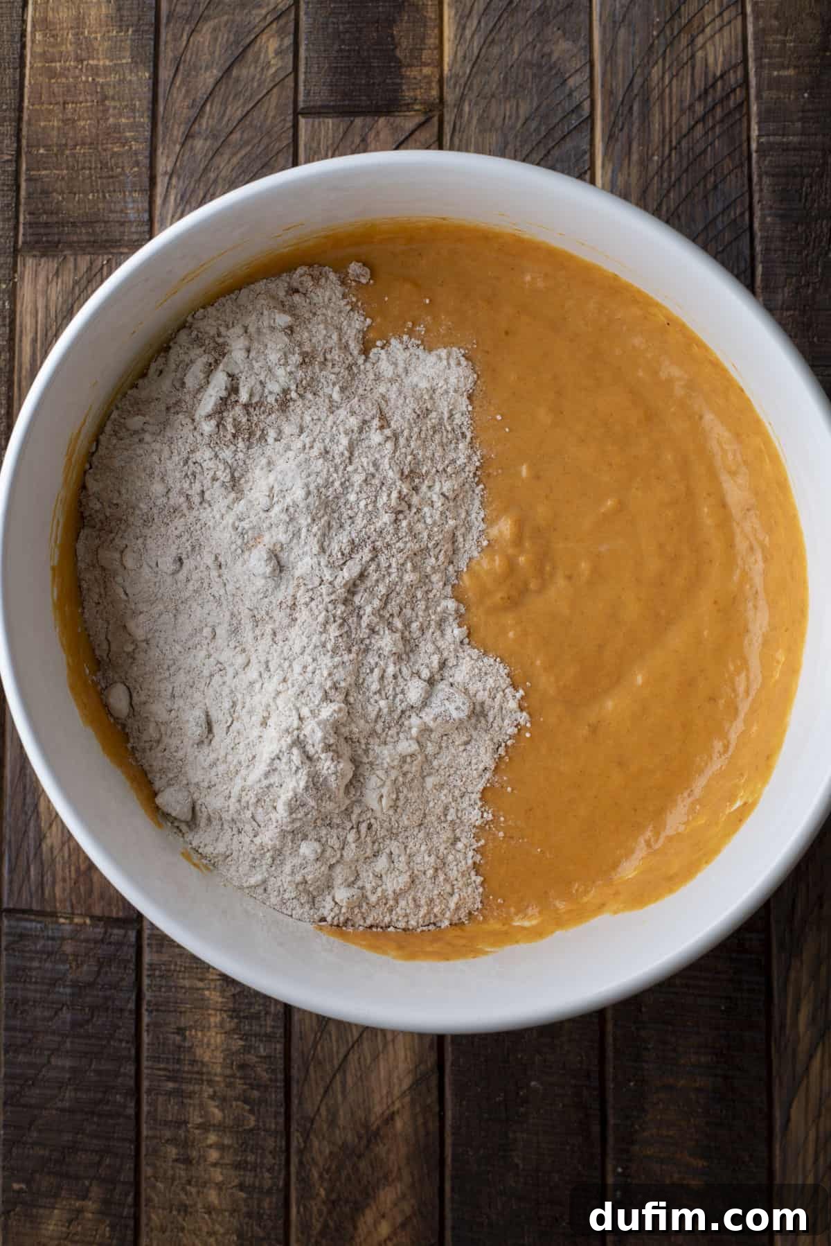 wet ingredients and dry ingredients for pumpkin muffins in a large white bowl, not combined yet