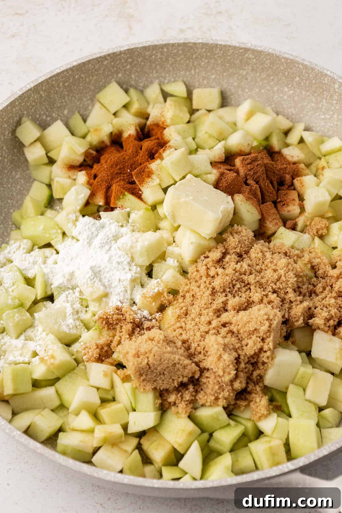 Golden Flaky Apple Turnovers 5 Finely diced apples, brown sugar, cinnamon, and nutmeg beautifully mixed in a large bowl, ready for cooking.
