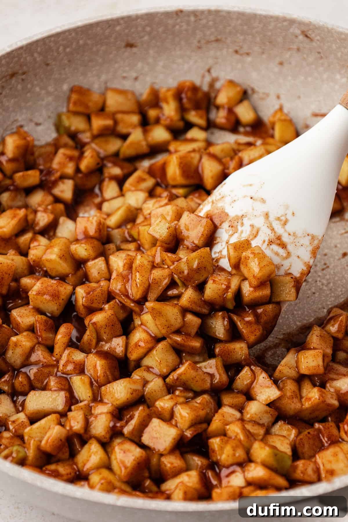 Golden Flaky Apple Turnovers 6 The spiced apple filling mixture simmering gently in a pan on the stove, showing the apples softening and the sauce thickening.