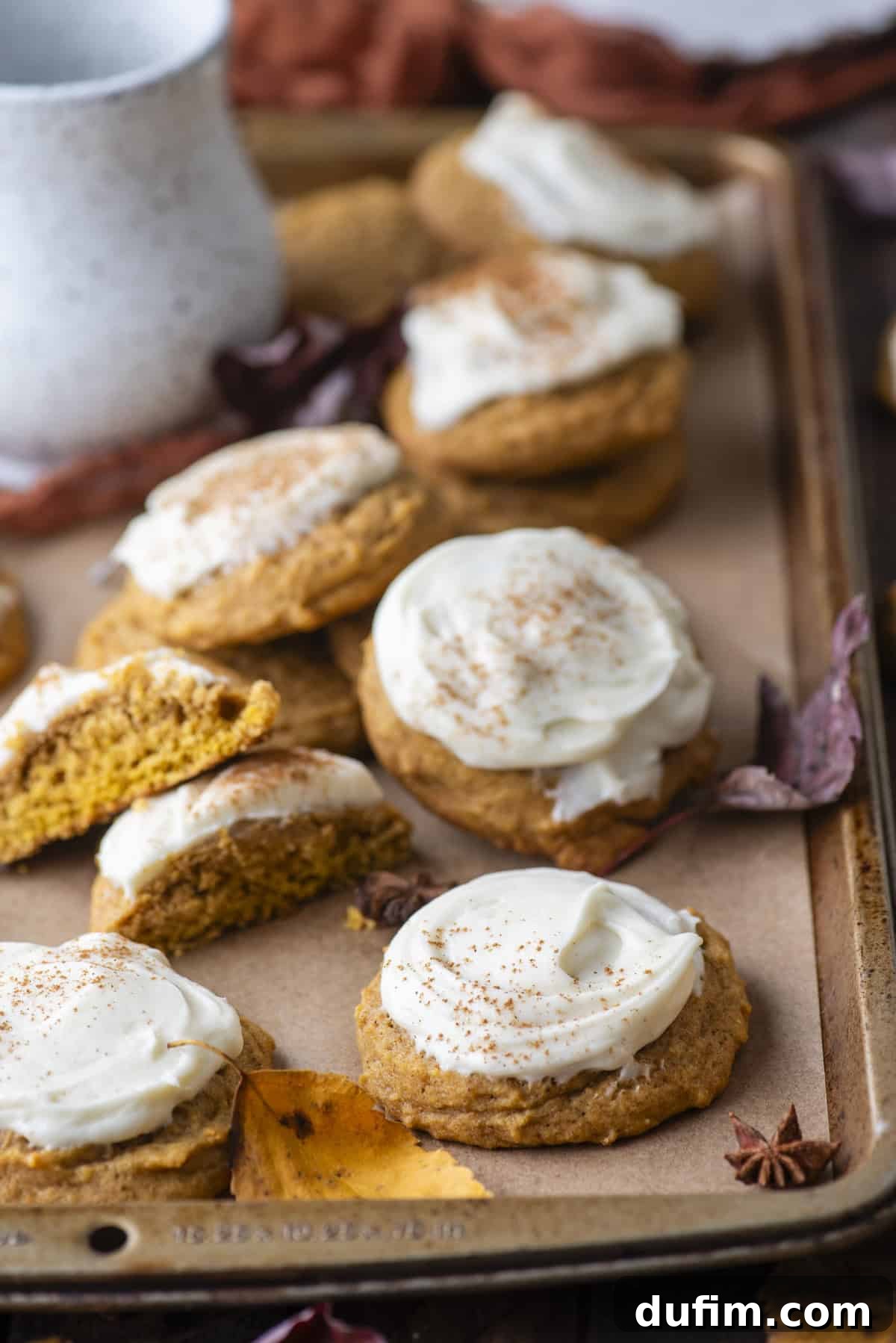 Cozy Autumn Pumpkin Spice Cookies 2 pumpkin cookies scattered around on a baking sheet surrounded by fall leaves and star anise