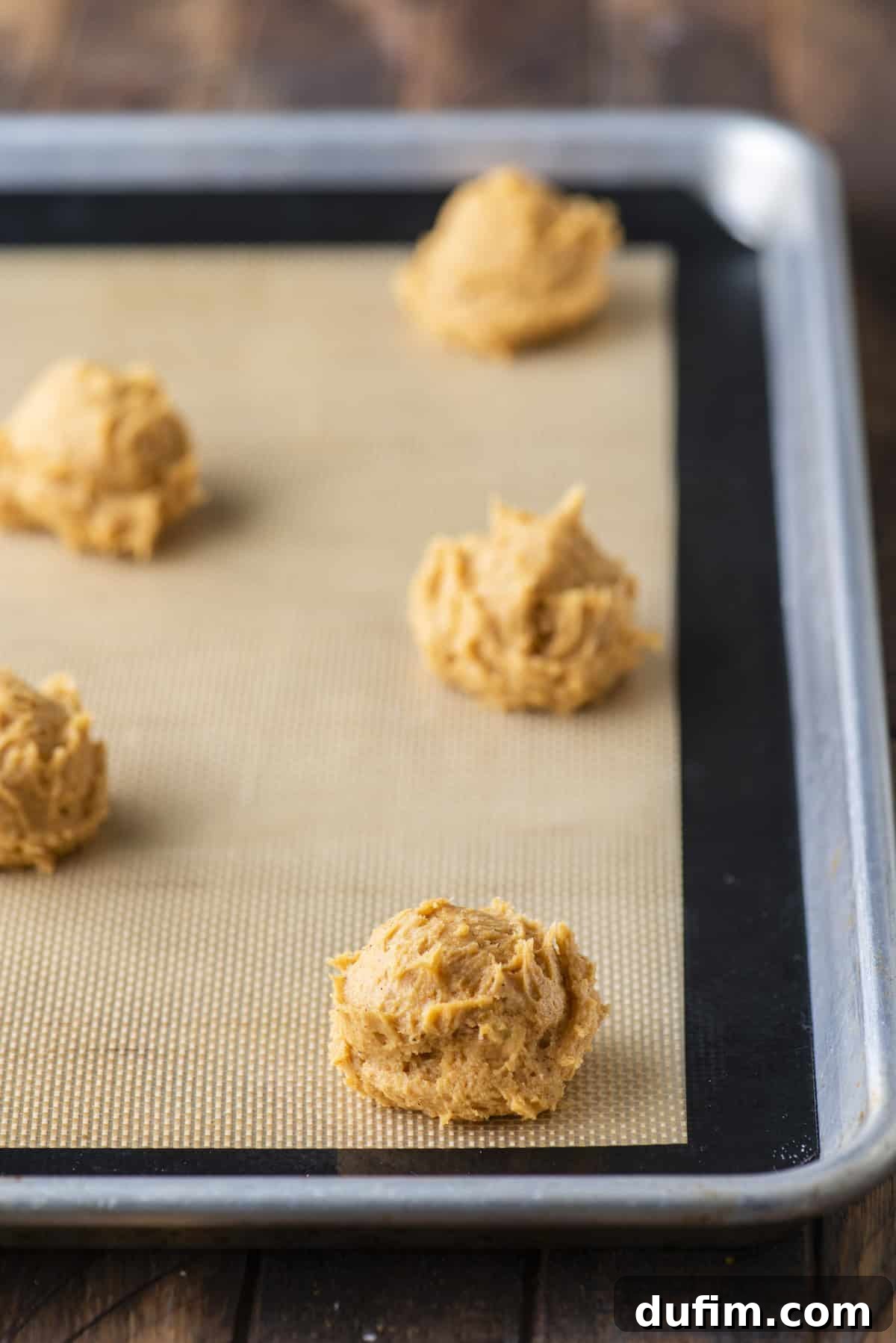 Cozy Autumn Pumpkin Spice Cookies 12 rows of pumpkin cookie dough balls on a baking sheet lined with a silicone baking mat