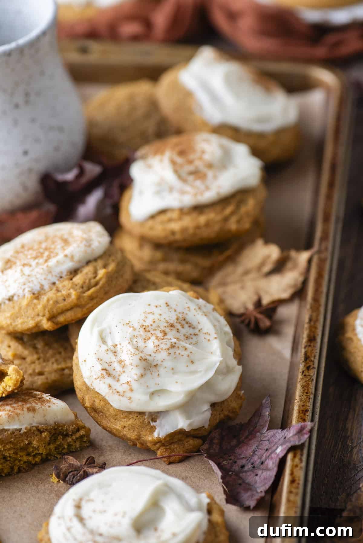 Cozy Autumn Pumpkin Spice Cookies 16 pumpkin cookies scattered around on a baking sheet surrounded by fall leaves and star anise