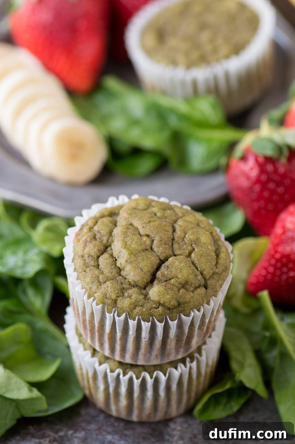 Two vibrant green spinach muffins stacked on top of each other, set against a dark background, highlighting their unique color and appealing texture.