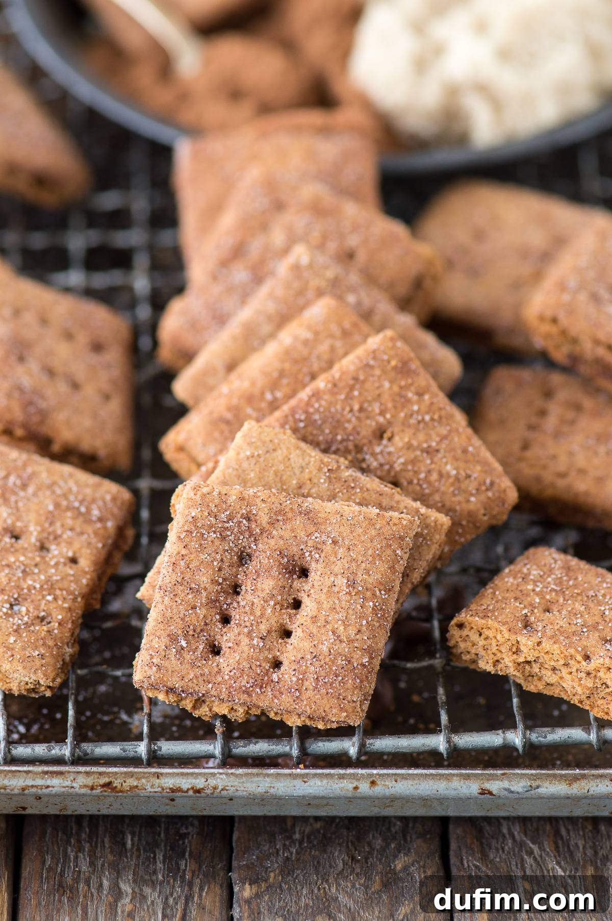 A beautiful stack of golden brown homemade brown sugar cinnamon graham crackers, glistening with sugar, on a rustic wooden surface.