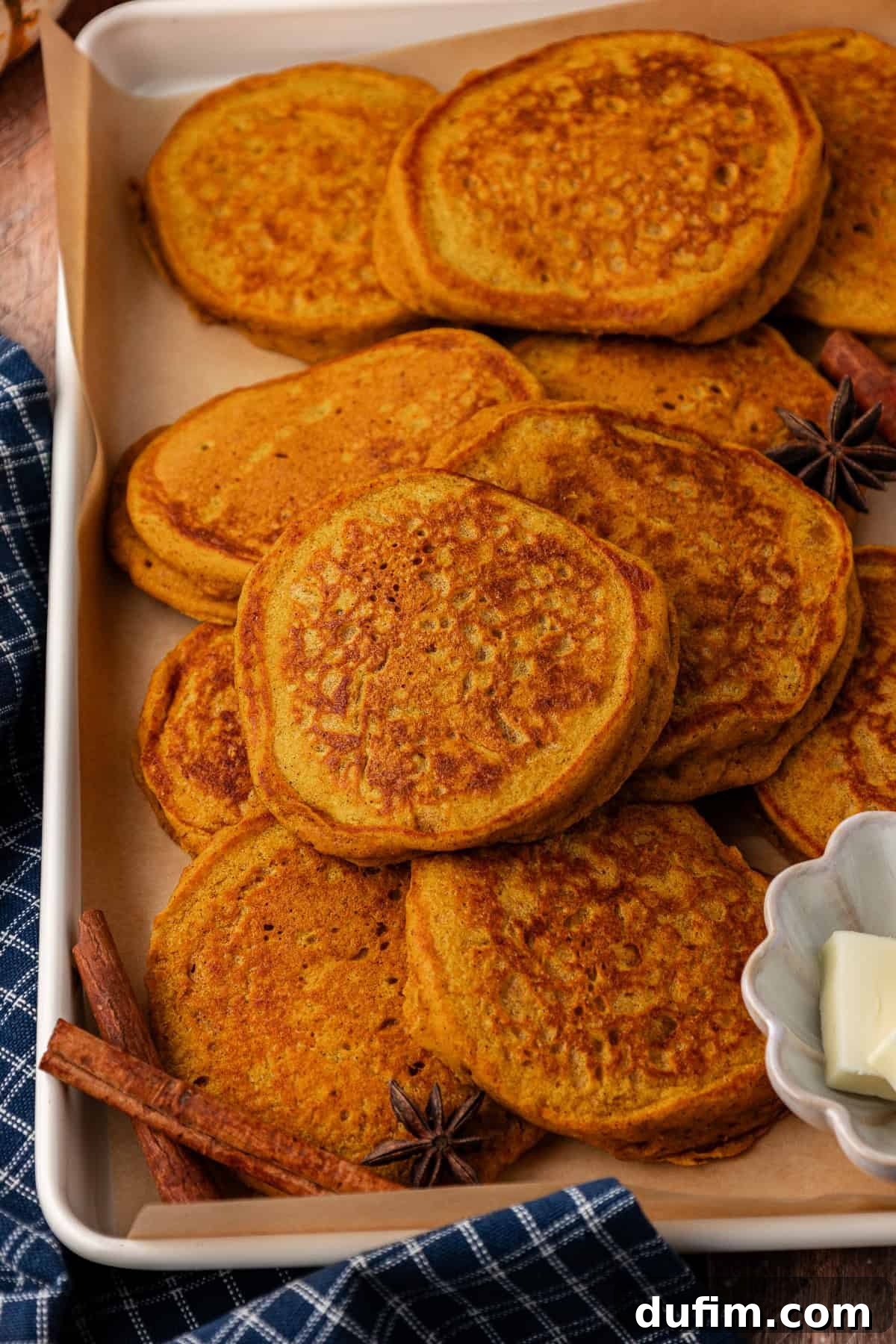 A delectable stack of pumpkin pancakes, garnished with cinnamon sticks and star anise, ready to be enjoyed as a perfect Fall breakfast.