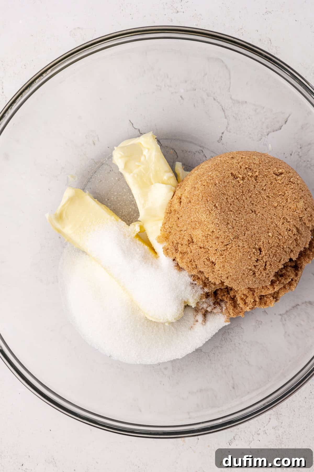 Butter, granulated sugar and brown sugar in a clear glass bowl