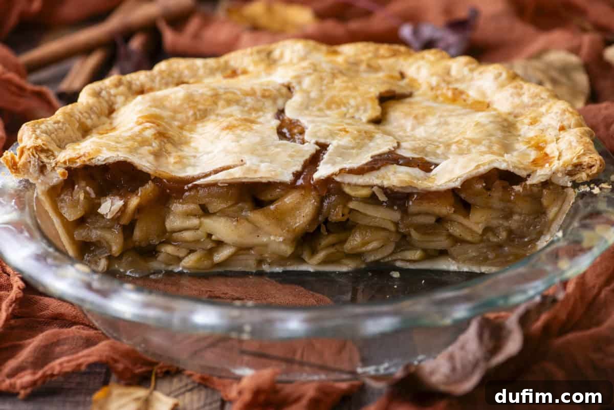 A close-up view of a half-eaten apple pie in its pie dish, revealing the perfectly cooked, glistening apple filling and the beautiful, flaky crust within, enticing viewers to take a bite.