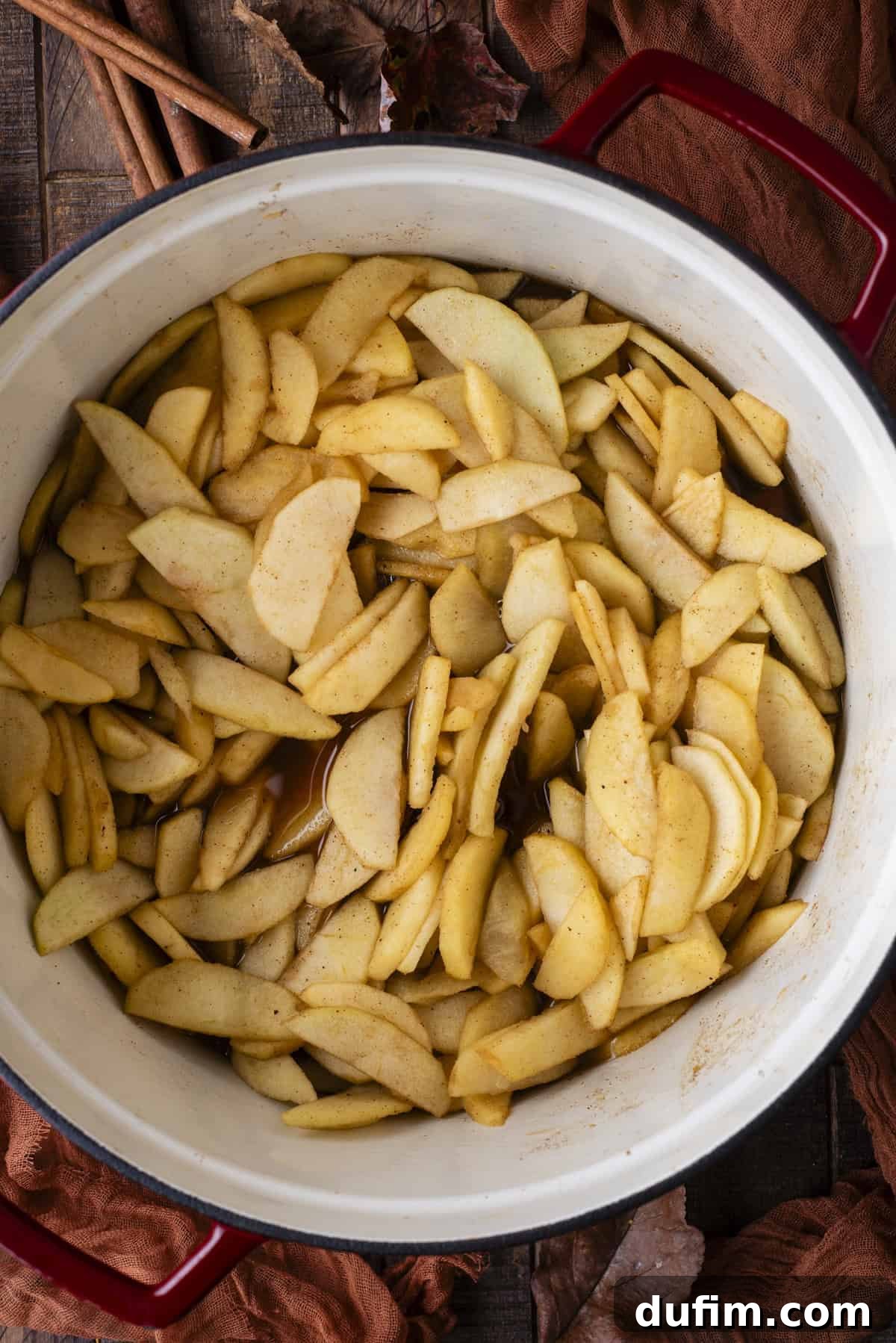 A close-up overhead shot of aromatic apple slices, tender and perfectly spiced, being cooked in a large pot, releasing their delicious juices and fragrance.