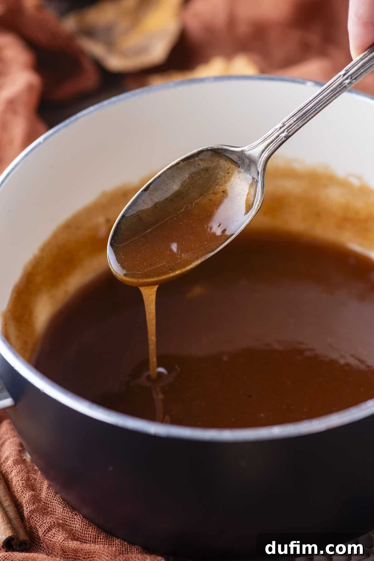 A saucepan filled with golden, viscous syrup, with a spoon gently drizzling more syrup back into the pan, highlighting its perfect consistency.