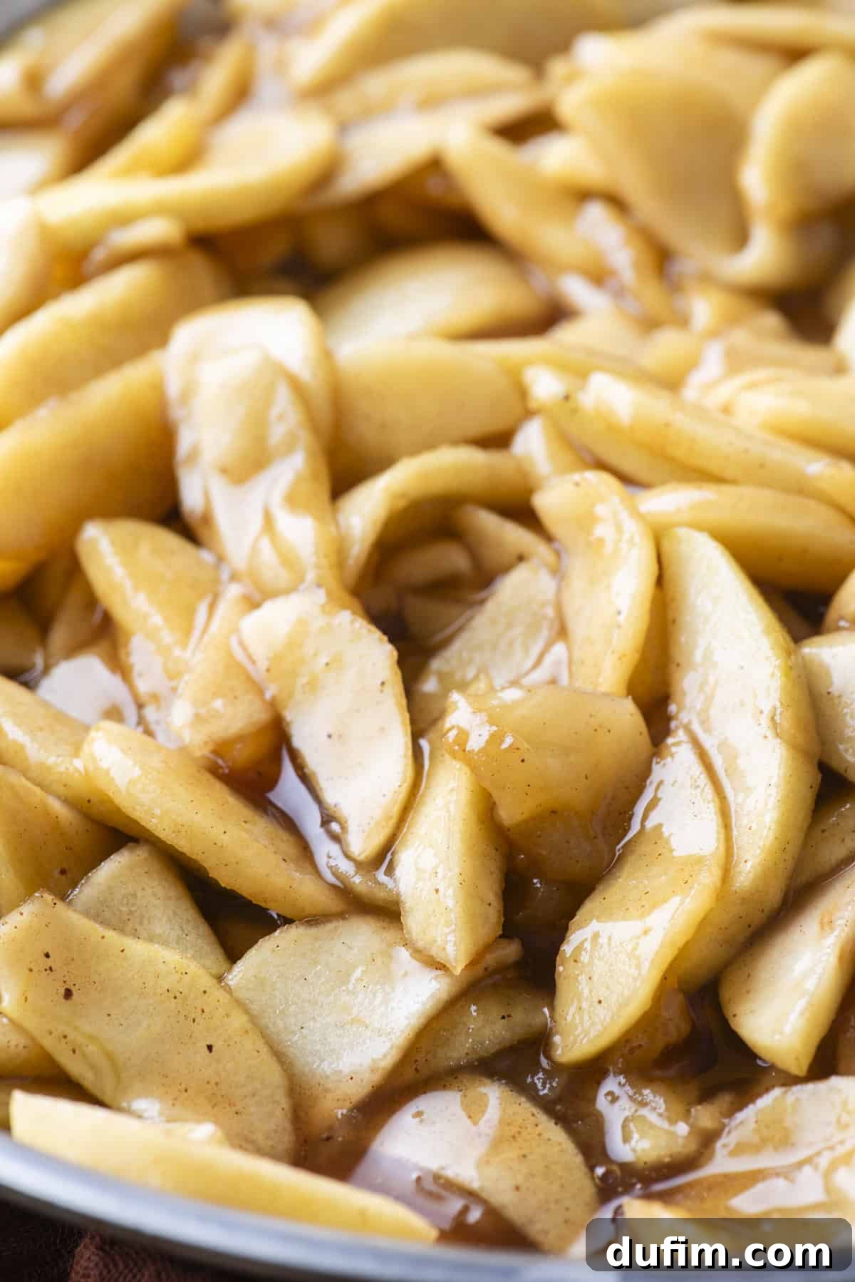 A close-up view of the rich, glossy apple pie filling, showcasing its tender apple slices and thick syrup.