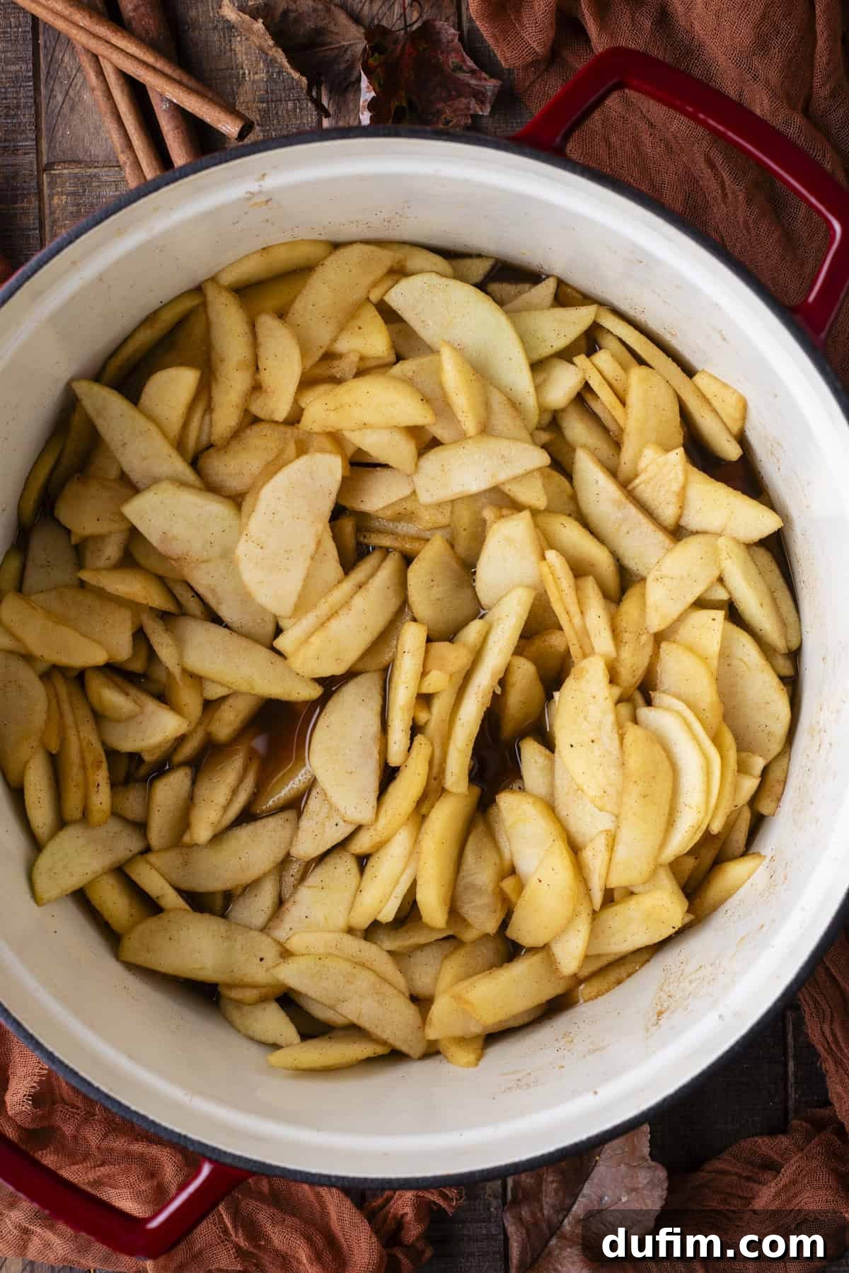 Overhead view of gently cooked apple slices, now softened and aromatic, resting in a large pot after simmering.