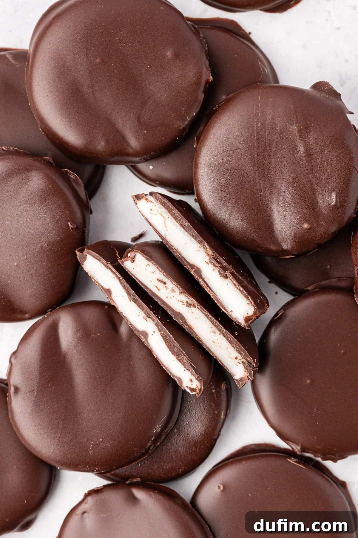 Cool & Creamy Homemade Peppermint Patties 15 A creative arrangement of scattered and stacked peppermint patties, with three halves positioned in the center, clearly displaying their refreshing white peppermint filling.