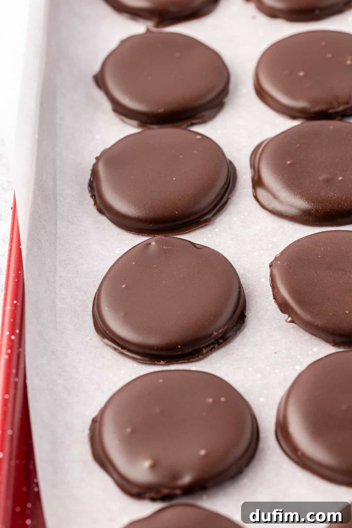 Cool & Creamy Homemade Peppermint Patties 16 Neat rows of freshly coated peppermint patties arranged on a baking pan lined with parchment paper, allowing the chocolate to set.