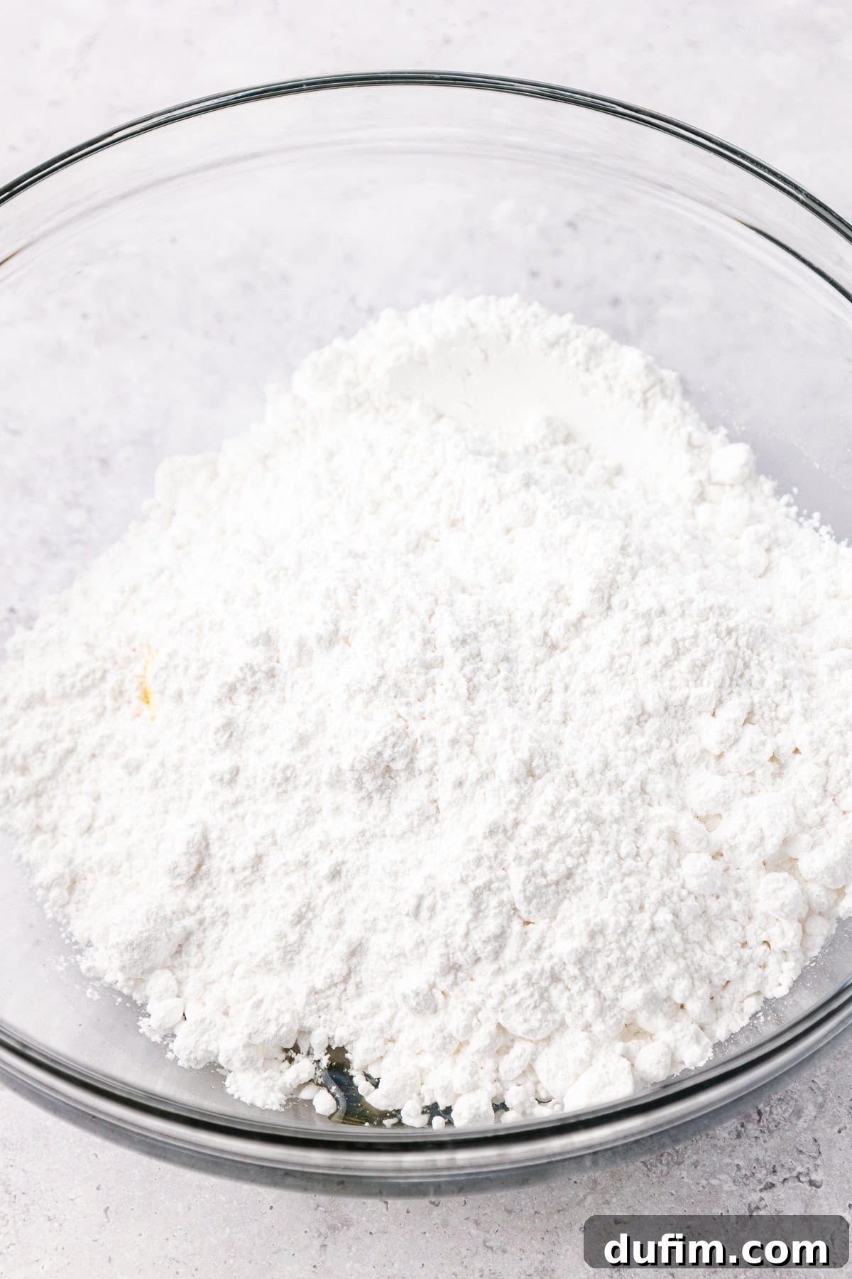Cool & Creamy Homemade Peppermint Patties 7 A mound of finely sifted powdered sugar resting in a clear glass bowl, an essential ingredient for the peppermint patty filling.
