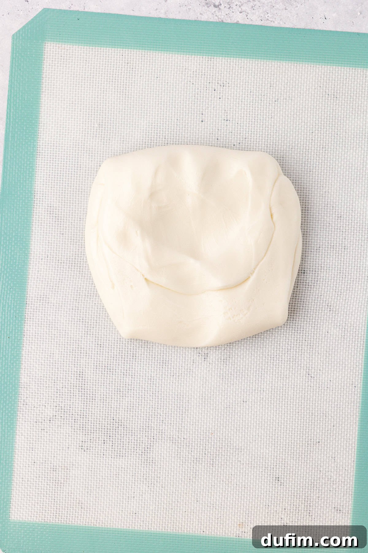 Cool & Creamy Homemade Peppermint Patties 9 A smooth, white ball of peppermint patty dough resting on a silicone mat, indicating it's perfectly kneaded and ready for shaping.