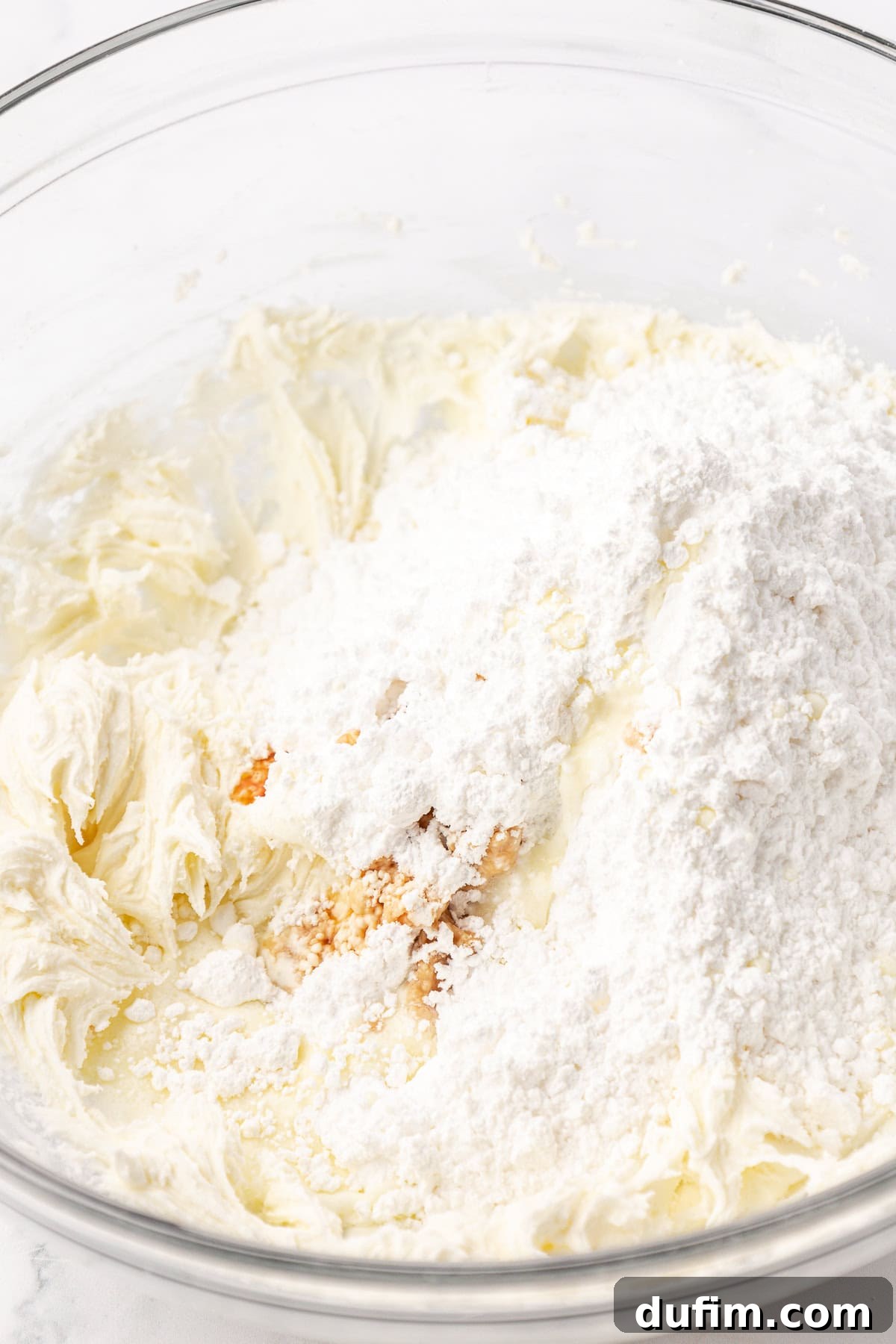 Melt-In-Your-Mouth Butter Mints 11 All the remaining ingredients for butter mints—powdered sugar, heavy cream, and extracts—ready to be combined with the initial butter mixture in a clear glass bowl.