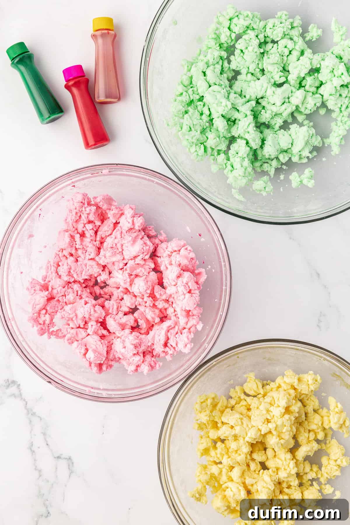 Melt-In-Your-Mouth Butter Mints 14 An overhead view of three glass bowls, each containing butter mint dough colored with different pastel food colorings: green, pink, and yellow, ready for shaping.