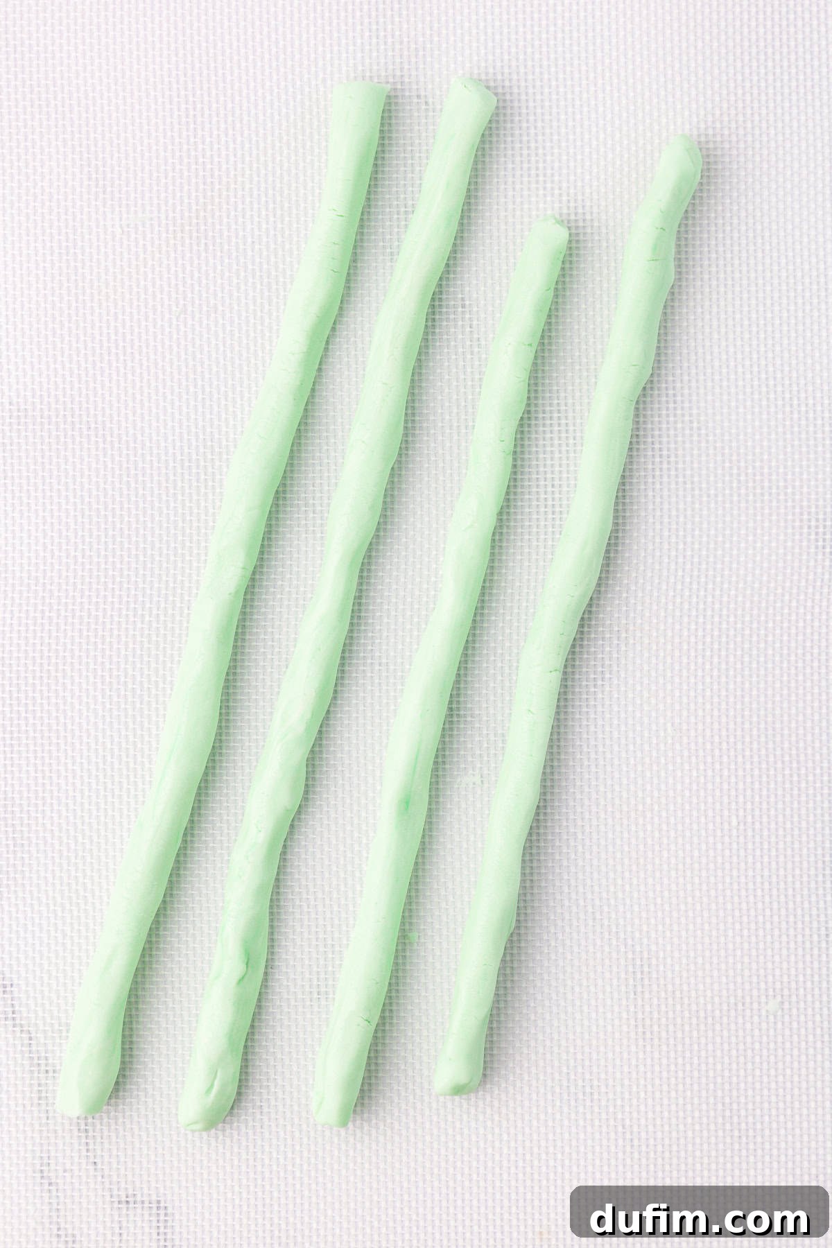 Melt-In-Your-Mouth Butter Mints 15 Four uniform ropes of light green butter mint dough, perfectly rolled and waiting to be cut, laid out on a clean white silicone mat.