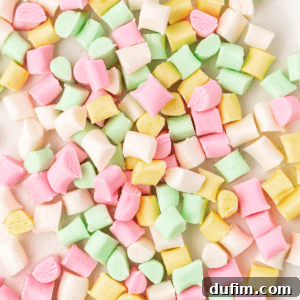 Close up of a pile of pink, white, yellow and green butter mints, showcasing their pastel colors and soft texture.