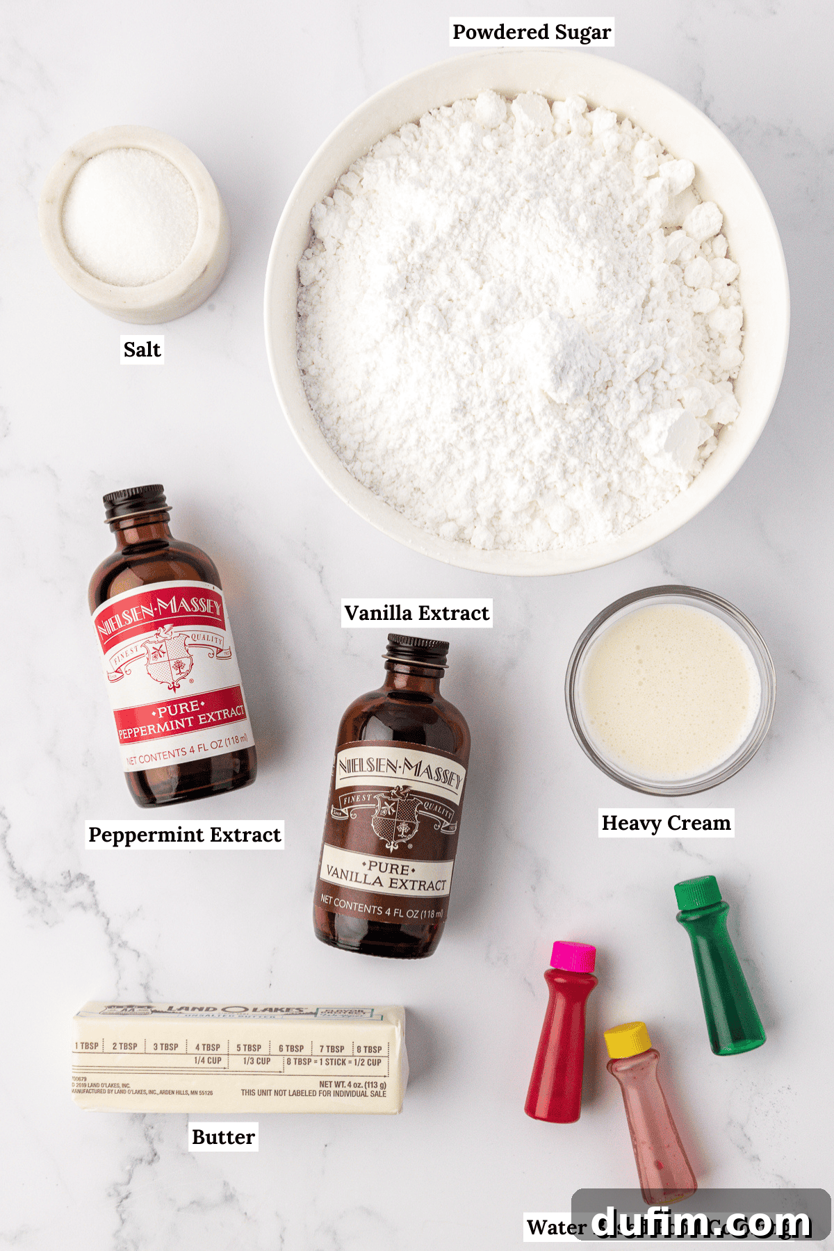 Melt-In-Your-Mouth Butter Mints 5 An overhead view of the essential ingredients for butter mints: powdered sugar, salt, peppermint extract, vanilla extract, heavy cream, softened butter, and a selection of water-based food coloring bottles.