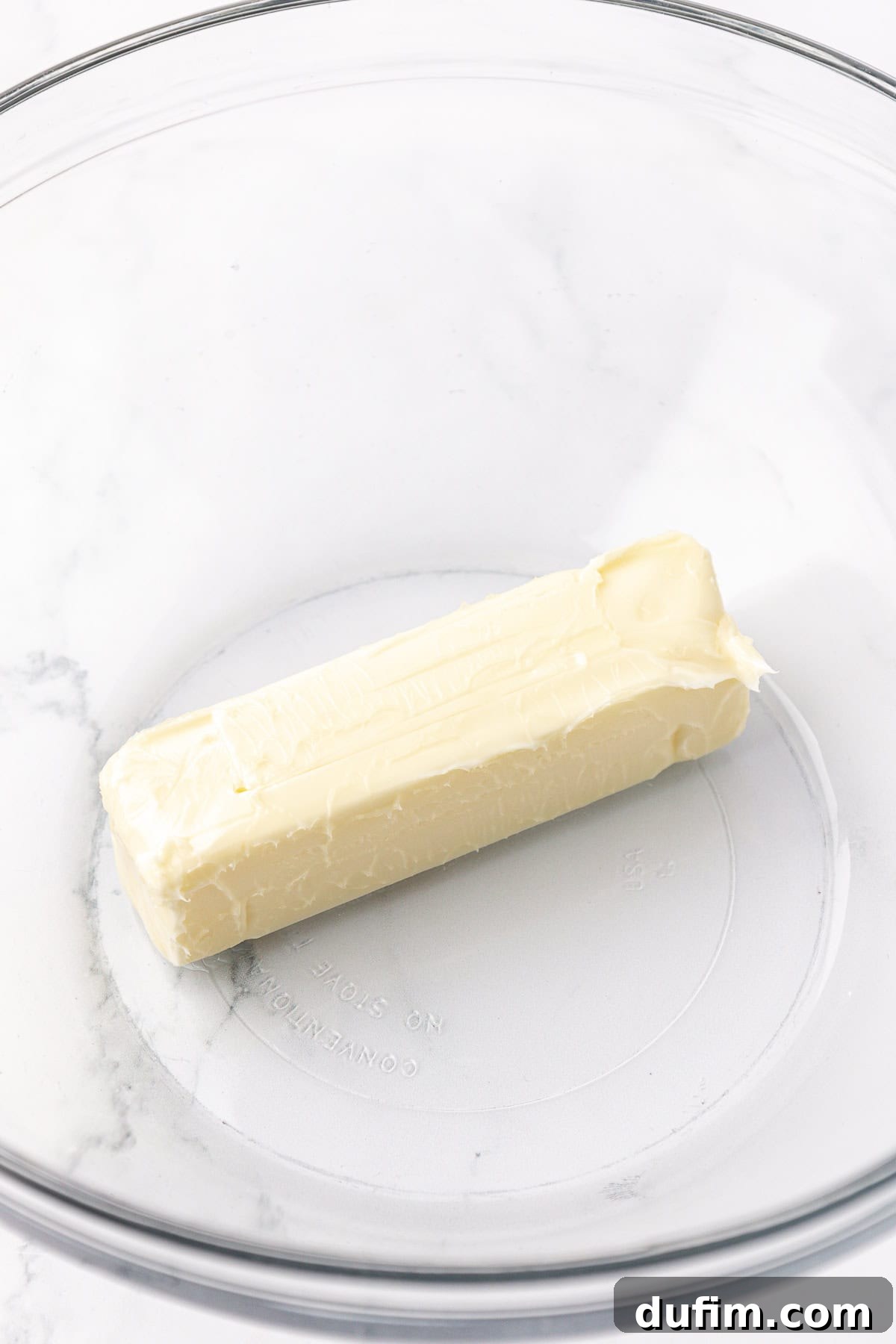 Melt-In-Your-Mouth Butter Mints 7 A single stick of softened butter resting in a clear glass mixing bowl, ready for creaming.