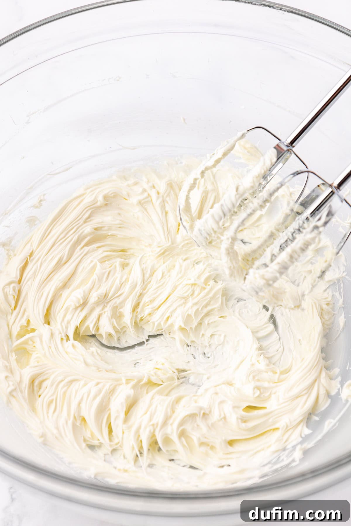 Melt-In-Your-Mouth Butter Mints 8 Close-up of butter being creamed in a clear glass bowl with an electric mixer, illustrating the start of the butter mint dough preparation.