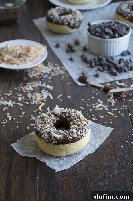A beautifully glazed coconut donut with chocolate ganache and toasted coconut, ready to eat.