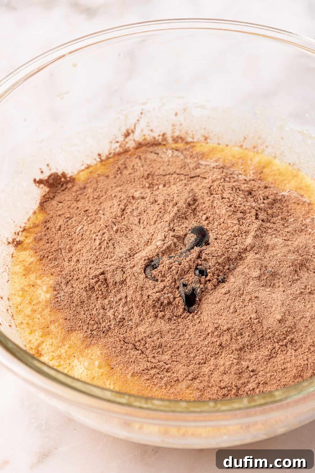 wet and dry ingredients in a clear glass mixing bowl not yet combined