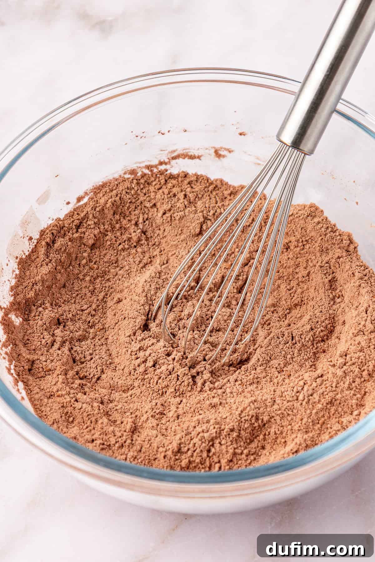 dry ingredients in a clear glass mixing bowl with a whisk