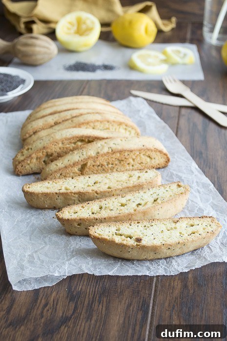 A stack of freshly baked lemon poppy seed biscotti on a rustic surface.