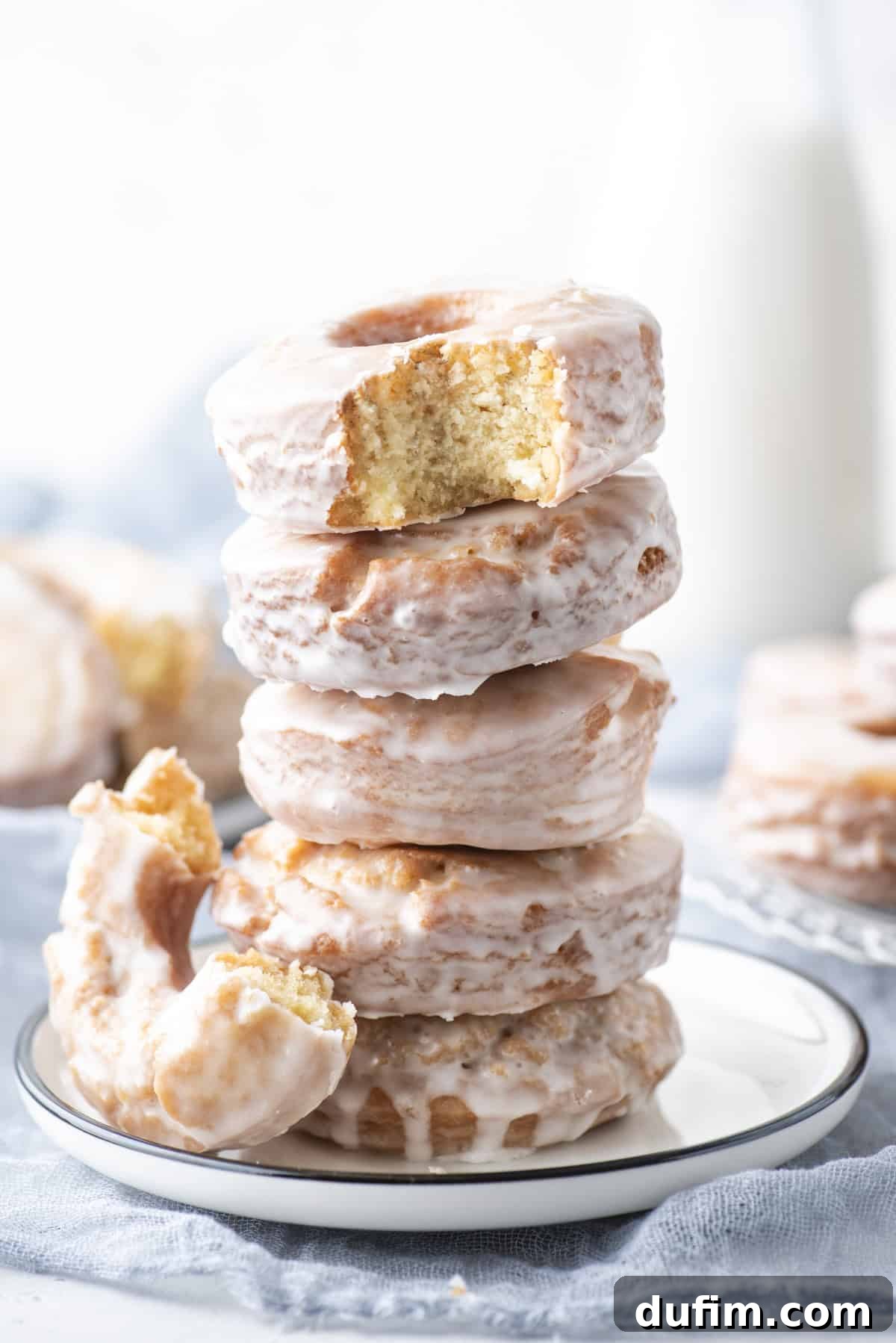 Effortless Donut Glaze Perfection 17 A perfectly stacked trio of glazed donuts on a plate, with a tempting bite taken from the top one.